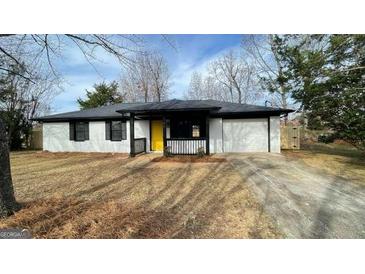 Charming single-story home featuring a yellow front door and well-maintained lawn at 95 Grove Creek Dr, Locust Grove, GA 30248