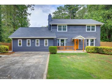 Charming two-story home featuring a gray exterior, well-manicured lawn, and bright orange front door at 317 Lucan Way, Riverdale, GA 30274