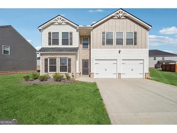 Inviting two-story home featuring a two-car garage, manicured lawn, and a mix of brick and siding exterior at 106 Cowpen Ct, Walnut Grove, GA 30052