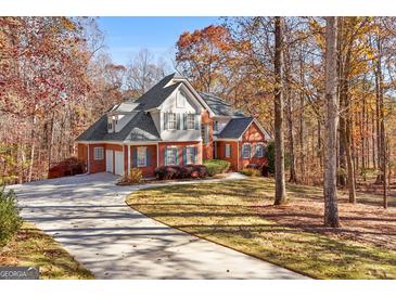 Charming two-story brick home featuring an attached garage, mature trees, and a long, winding driveway at 340 Antebellum Way, Fayetteville, GA 30215