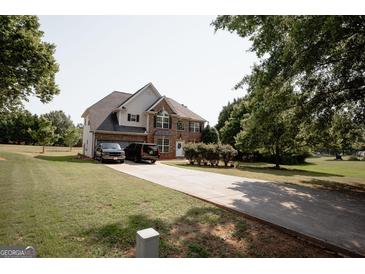 Brick two-story home featuring a long driveway and mature landscaping at 424 Norman Ct, Hampton, GA 30228