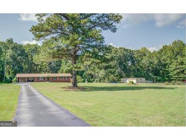 Well-maintained brick home with a spacious front yard and mature trees at 677 Gum Creek Rd, Oxford, GA 30054