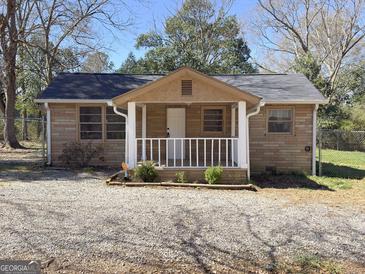 Charming single-story home with a gravel driveway and a cozy front porch at 927 Dean Patrick Rd, Locust Grove, GA 30248