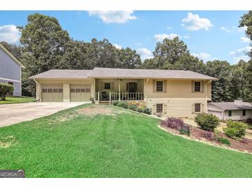 Charming ranch home featuring a two-car garage, covered porch, and mature trees at 3231 Boulder Brook Dr, Lithonia, GA 30038