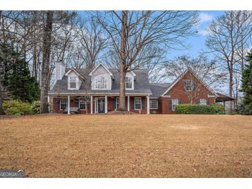 Charming brick home with a covered front porch and mature trees on a large lawn at 149 Crown Oaks Dr, Stockbridge, GA 30281