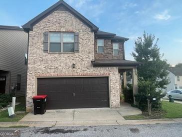 Two-story brick home featuring an attached two-car garage and manicured landscaping at 6001 Nile Ct, Atlanta, GA 30349