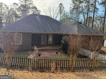 A brick home with a cozy backyard patio space and a charming white picket fence at 5207 Sw West Shore Dr, Conyers, GA 30094