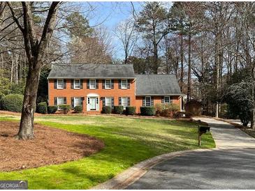 Charming two-story brick home featuring a manicured lawn and mature trees at 1121 Valley Ridge, Marietta, GA 30067