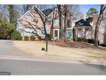 Charming brick home with a well-manicured lawn, mature trees, and a welcoming blue front door at 365 Falling Creek Bnd, Johns Creek, GA 30097