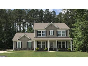Charming two-story home with a well-manicured lawn and inviting front porch with stone accents at 85 Crabapple Ridge Dr, Oxford, GA 30054