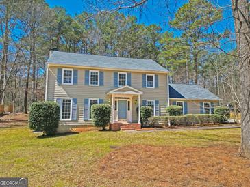 Charming two-story home with blue shutters, a gray roof, and professionally landscaped yard on a sunny day at 175 Ashley Dr, Fayetteville, GA 30214