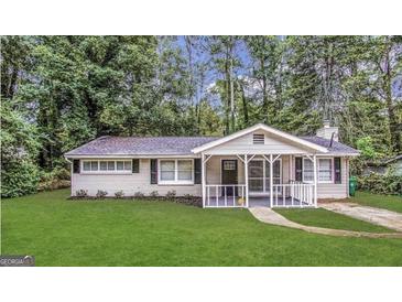 Charming single-story home with a welcoming porch, surrounded by lush greenery and a well-manicured lawn at 3395 Longleaf Dr, Decatur, GA 30032