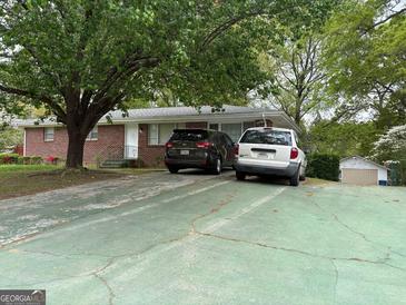 Charming brick ranch-style home with a spacious driveway and mature trees, offering a serene setting at 6826 Mayo Dr, Riverdale, GA 30274