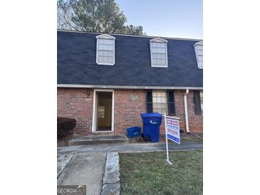 Charming townhome with brick facade, dormer windows and 'For Sale' sign in the front yard at 138 Plantation Cir, Clarkston, GA 30021