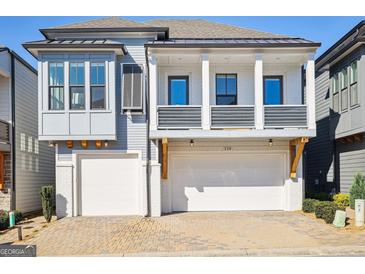 Beautiful new home features a two-car garage, covered front porch, and gray siding at 114 Village Green Ave, Woodstock, GA 30189