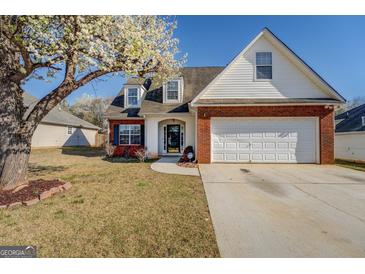 Charming home featuring a brick facade, two-car garage, flowering tree, and well-maintained lawn at 6380 Winston Trce, Mcdonough, GA 30252