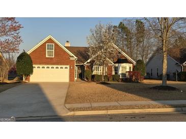 Charming brick home featuring an attached two-car garage and a blossoming tree in the landscaped front yard at 1006 Harbor View Ln, Mcdonough, GA 30252