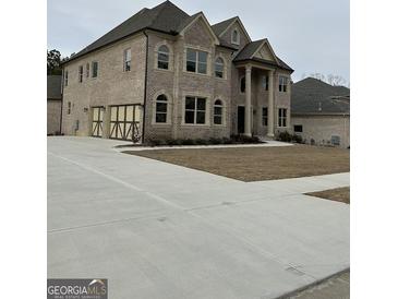 Two-story brick home with a prominent entrance featuring columns and arched windows, plus an attached two car garage at 829 Artistry Way, Fairburn, GA 30213