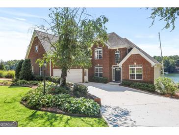 Beautiful brick home with a well-manicured lawn, mature trees, and a two-car garage with direct water access at 1283 Heritage Dr, Villa Rica, GA 30180