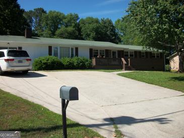 Charming single-story home features a green roof, brick accents, and a spacious driveway, offering comfortable suburban living at 10174 Twin Oaks Sw Dr, Covington, GA 30014