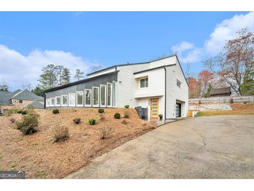 Striking modern home featuring a unique architectural design, multi-pane windows, and a driveway to the attached garage at 3365 Turtle Lake Se Dr, Marietta, GA 30067