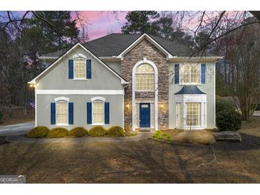 Charming two-story home featuring a stone facade, complemented by blue shutters and a well-manicured lawn at 2715 Ivey Crossing Trl, Cumming, GA 30041
