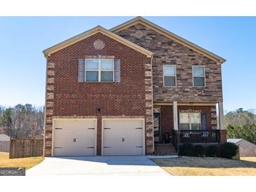 Two-story home featuring brick and stone details, a two-car garage, and a charming front porch at 1127 Lehavre Ct, Hampton, GA 30228