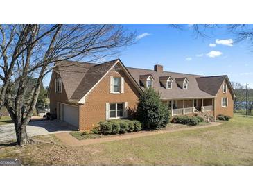 Beautiful brick home featuring an attached garage, well-manicured lawn, and lovely landscaping at 2940 E Lake Road, Mcdonough, GA 30252