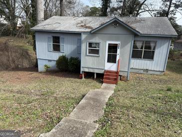 Quaint single-story home featuring a walkway to a covered front porch and blue exterior paint at 305 Creighton Ave, Scottdale, GA 30079