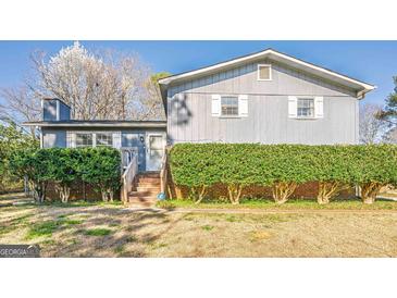 Charming two-story home with light blue siding and white trim surrounded by green hedges at 3006 Deshong Dr, Stone Mountain, GA 30087