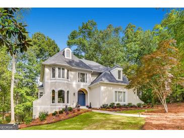 Charming two-story home boasts a blue front door, lush landscaping, and mature trees at 305 Worthing Lane, Mcdonough, GA 30253