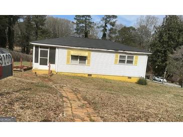 Charming single-story home with white siding, black roof, and bright yellow accents at 3100 Bay St, Scottdale, GA 30079