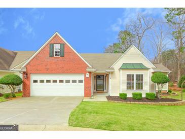 Charming home features a brick and siding exterior, two-car garage, and well-manicured lawn at 1067 Pinehurst Dr, Peachtree City, GA 30269