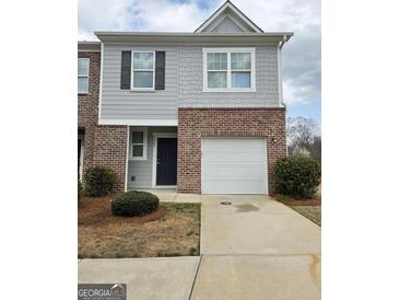 Charming townhome featuring a brick and siding exterior with an attached single car garage at 1463 River Stone Trce, Conyers, GA 30012