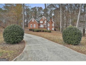 Charming two-story red brick home with well-manicured landscaping and a long driveway leading to the house at 165 Standing Oak Pl, Fayetteville, GA 30214