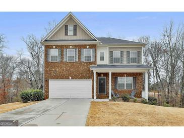 Charming two-story home with brick facade, white garage door and landscaped front yard at 130 Brooks Cir, Hampton, GA 30228