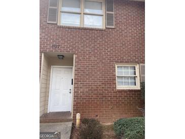 Exterior view of a two-story brick house with white door and brown shutters on a cloudy day at 4477 Golf Vista Cir, Decatur, GA 30035