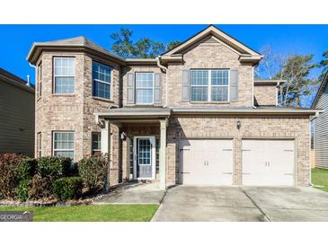 Charming brick two-story home with a well-manicured lawn and a two-car garage with decorative shutters at 7569 Bowhead Ct, Fairburn, GA 30213