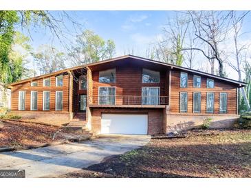 Unique two-story home with wood siding, brick accents, balcony, garage, and inviting curb appeal at 6290 Shallowford Way, Douglasville, GA 30135