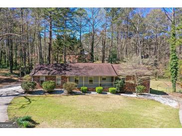 Charming home featuring a well-manicured lawn and a welcoming front porch, surrounded by mature trees and lush greenery at 9491 Hidden Branch Dr, Jonesboro, GA 30236