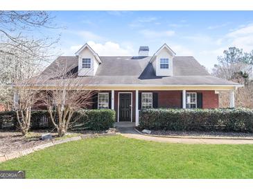Charming brick home with dormer windows, lush landscaping, and inviting front entrance at 136 Leguin Forest Dr, Locust Grove, GA 30248