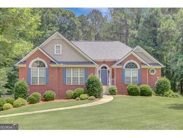 Charming brick home with a well-manicured lawn, blue shutters, and beautiful landscaping at 140 Rockglen Ct, Fayetteville, GA 30215