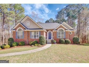 Charming brick home with a manicured lawn, complemented by lush greenery and inviting curb appeal at 140 Rockglen Ct, Fayetteville, GA 30215