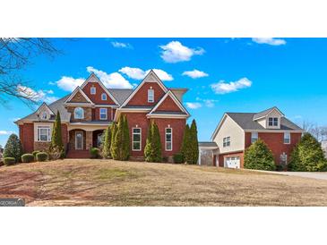 Elegant brick home on a landscaped lawn with blue sky and cloud background at 560 Birkdale Dr, Fayetteville, GA 30215