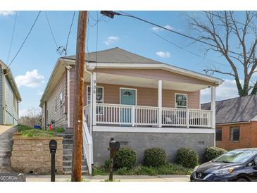 Charming home featuring a covered front porch with white railings and a light blue front door at 906 Sims Sw St, Atlanta, GA 30310