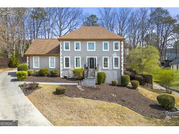 Charming two-story home with manicured lawn, mature trees, and a classic architectural design on a sunny day at 2840 Riverfront Dr, Snellville, GA 30039
