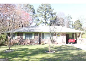 Charming brick home with a well-manicured lawn, carport, and decorative front yard at 6064 Monica Dr, Morrow, GA 30260