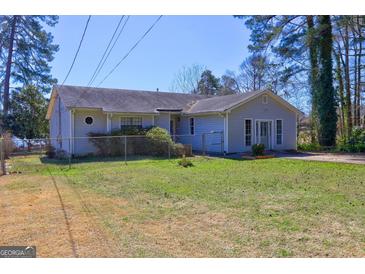Charming single-story home with a well-maintained lawn and a chain-link fence under a clear blue sky at 342 Lakeshore Dr, Stockbridge, GA 30281