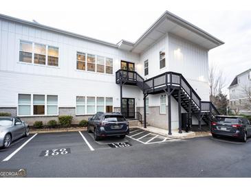 Modern white building with black stairs, complemented by ample parking spaces and manicured landscaping at 170 Fowler St # 200, Woodstock, GA 30188