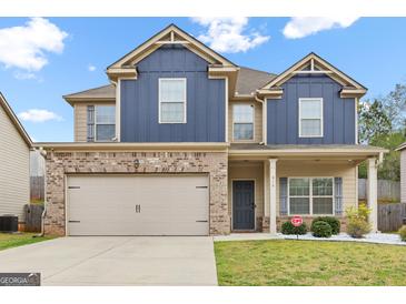 Charming two-story home with a brick and blue exterior, attached garage, and well-maintained lawn at 312 Maddi Grace Ct, Locust Grove, GA 30248